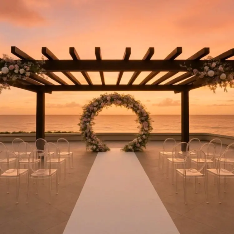 Oceanfront terrace wedding ceremony setup with floral arch at sunset, Secrets Mirabel Cancun