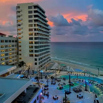 Secrets Mirabel pool terrace and beachfront towers lit at sunset, Cancun