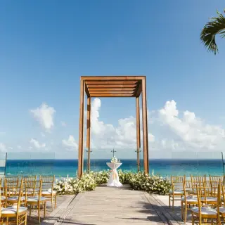 Oceanfront wedding ceremony setup with wooden gazebo and gold chairs at Secrets Moxche, Playa Del Carmen