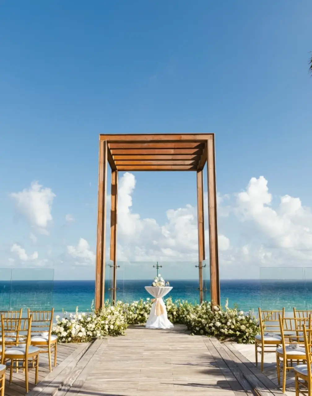 Oceanfront wedding ceremony setup with wooden gazebo and gold chairs at Secrets Moxche, Playa Del Carmen