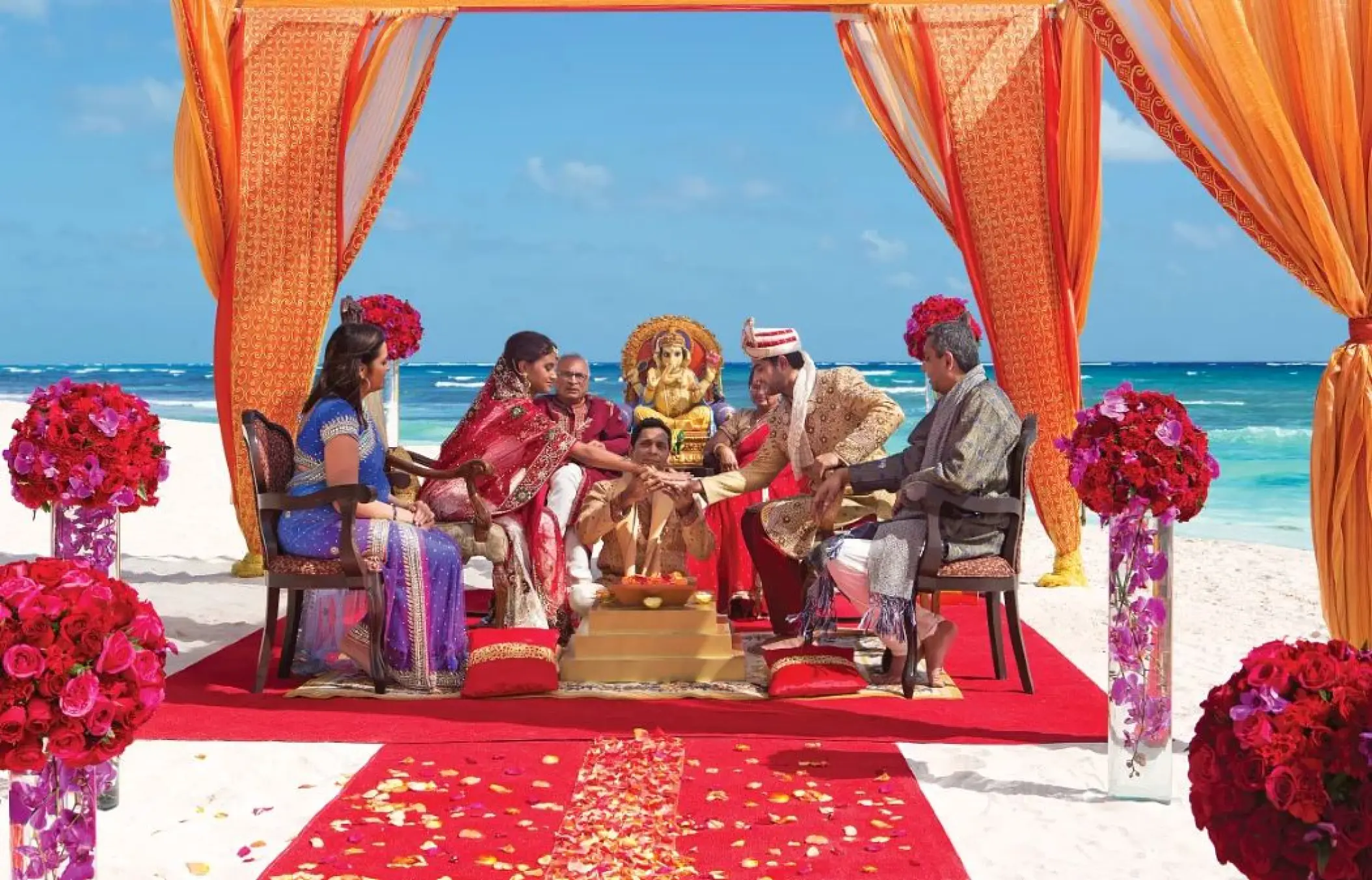 South Asian wedding ceremony under an orange mandap at Secrets Moxche, Playa Del Carmen