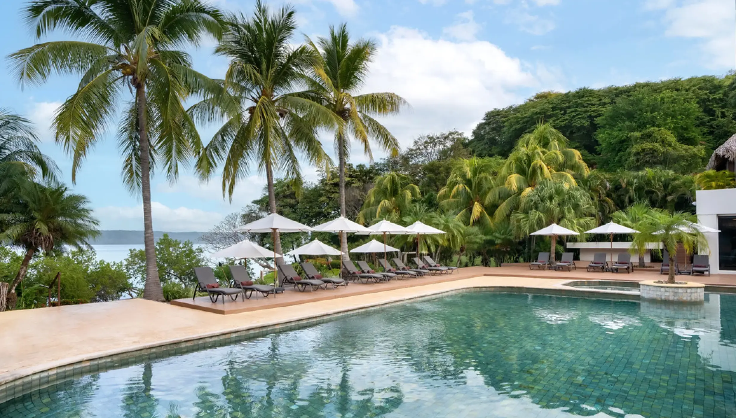 Spa pool and lounge chairs under umbrellas at Secrets Papagayo, Papagayo