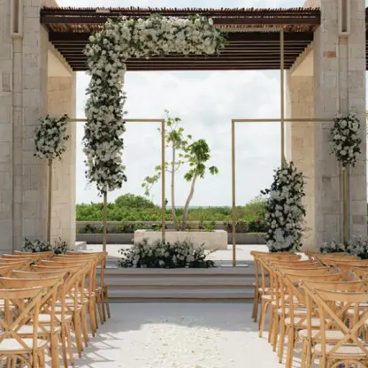 Courtyard plaza wedding ceremony with white floral arch and wooden chairs at Secrets Playa Blanca, Cancun