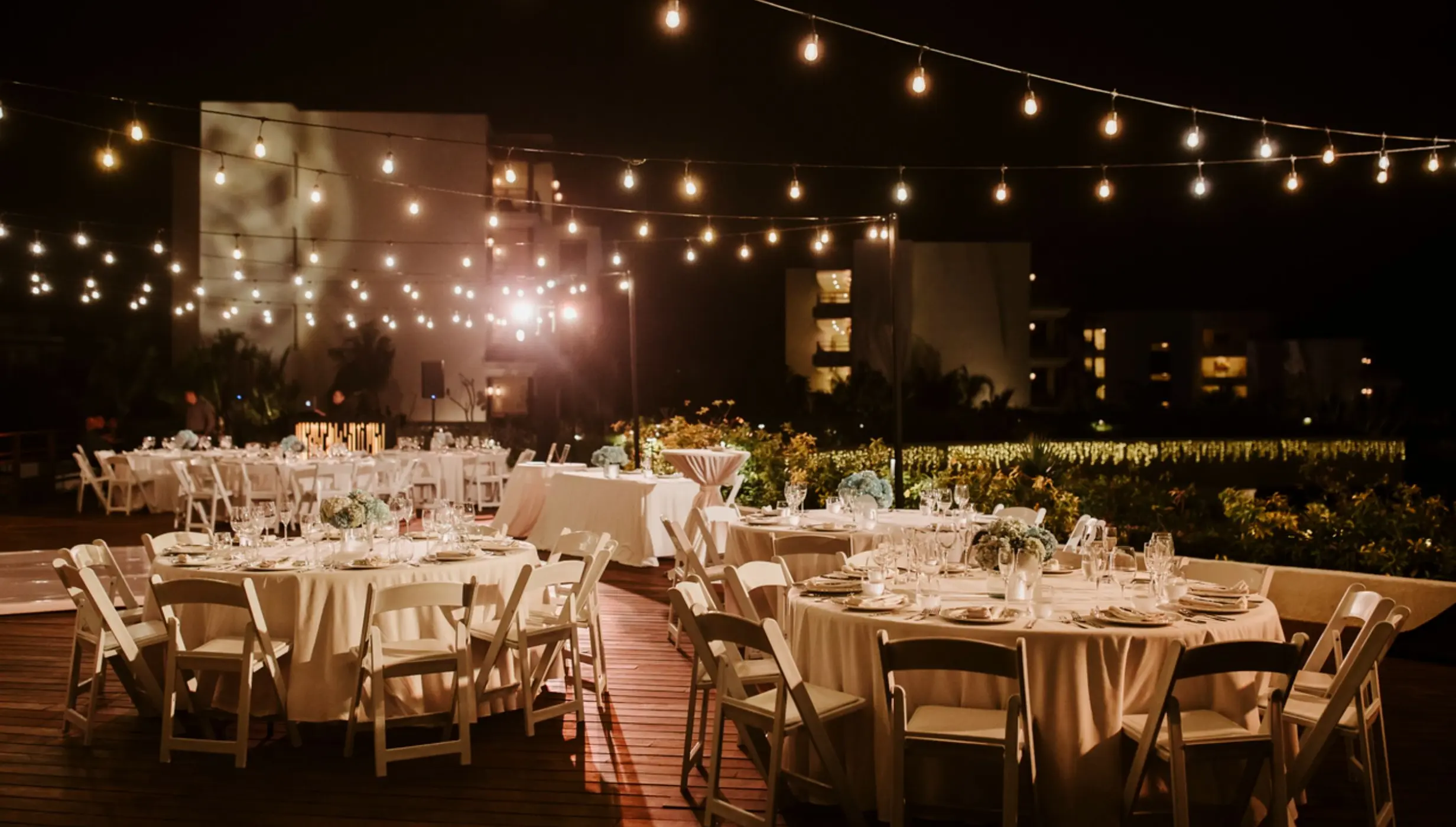 Rooftop wedding reception with string lights and round tables at Secrets Playa Blanca, Cancun