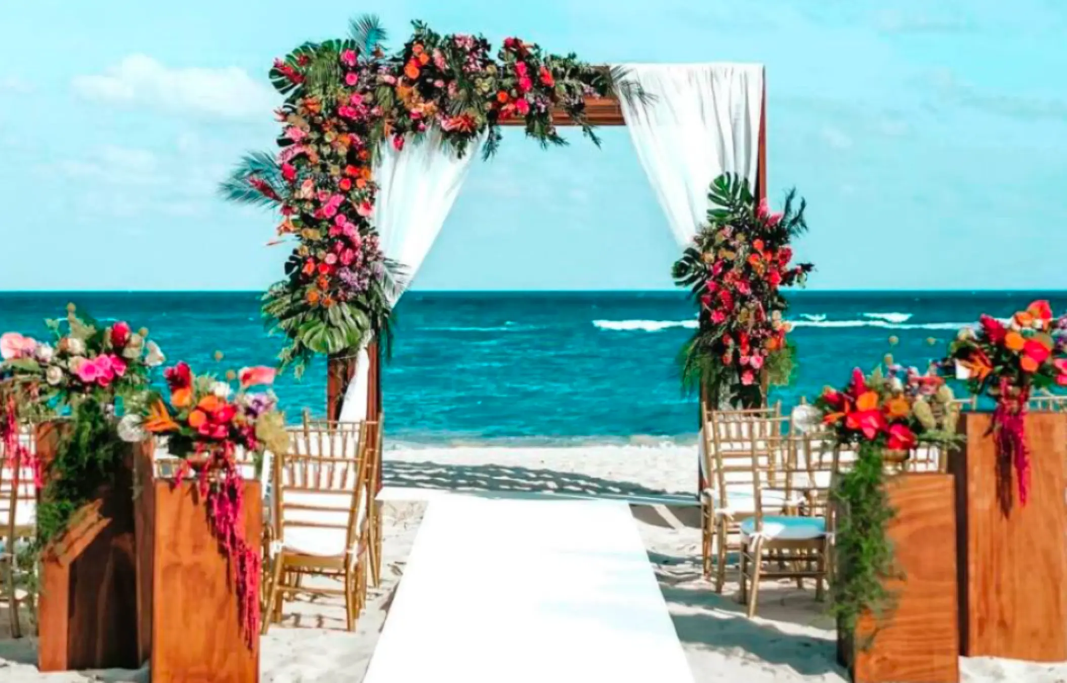 Beachfront wedding ceremony with floral arch and white aisle at Secrets Playa Blanca Costa Mujeres, Cancun