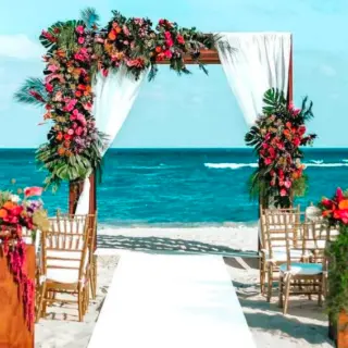Beachfront wedding ceremony with floral arch and white aisle at Secrets Playa Blanca Costa Mujeres, Cancun