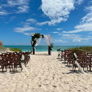 Beachfront wedding ceremony setup with wooden cross-back chairs at Secrets Playa Blanca, Cancun