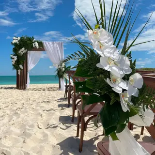 Beach wedding ceremony with white orchids and a wooden arch at Secrets Playa Blanca, Cancun