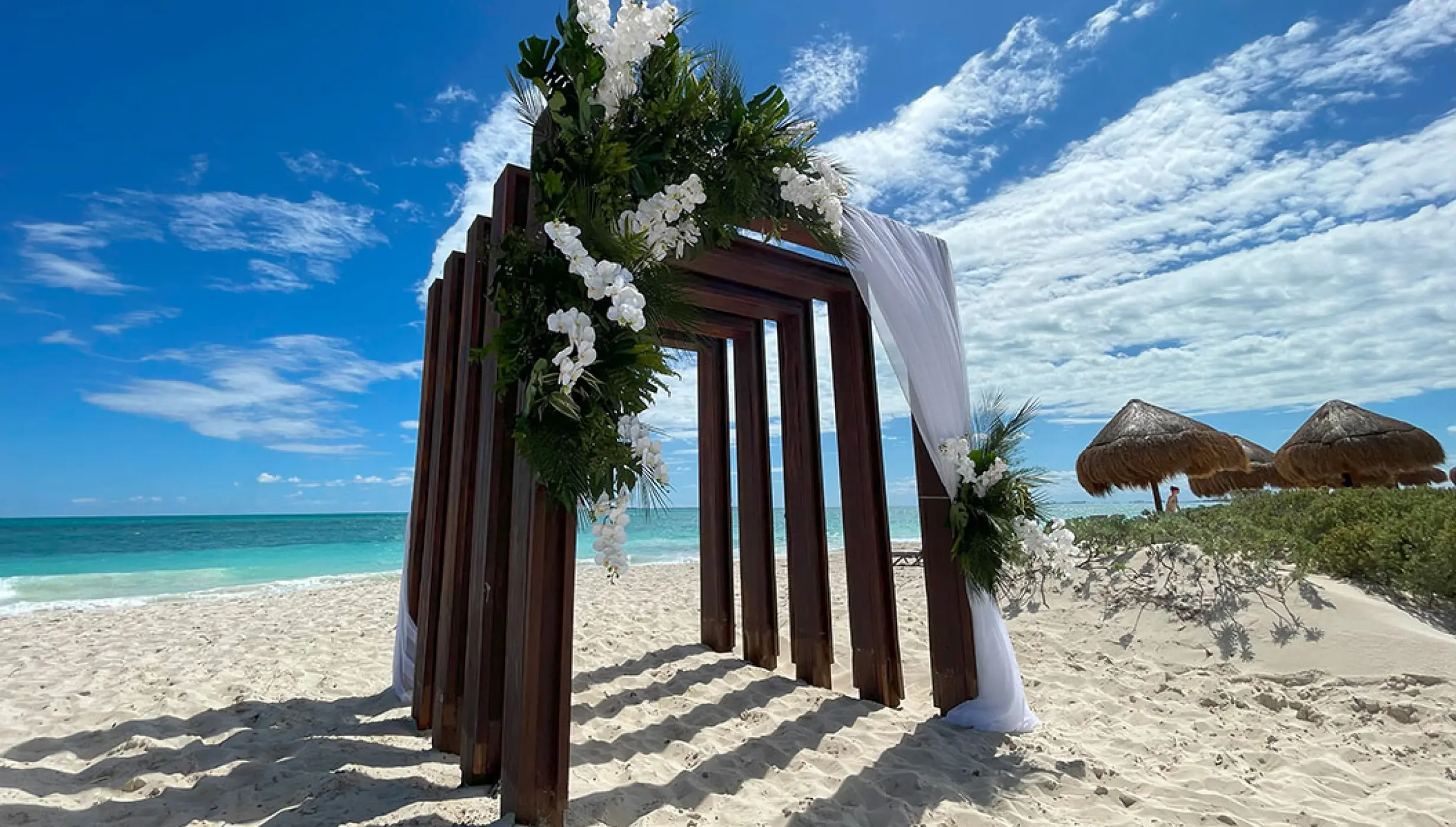 Wooden beach wedding ceremony arch with white flowers at Secrets Playa Blanca, Cancun