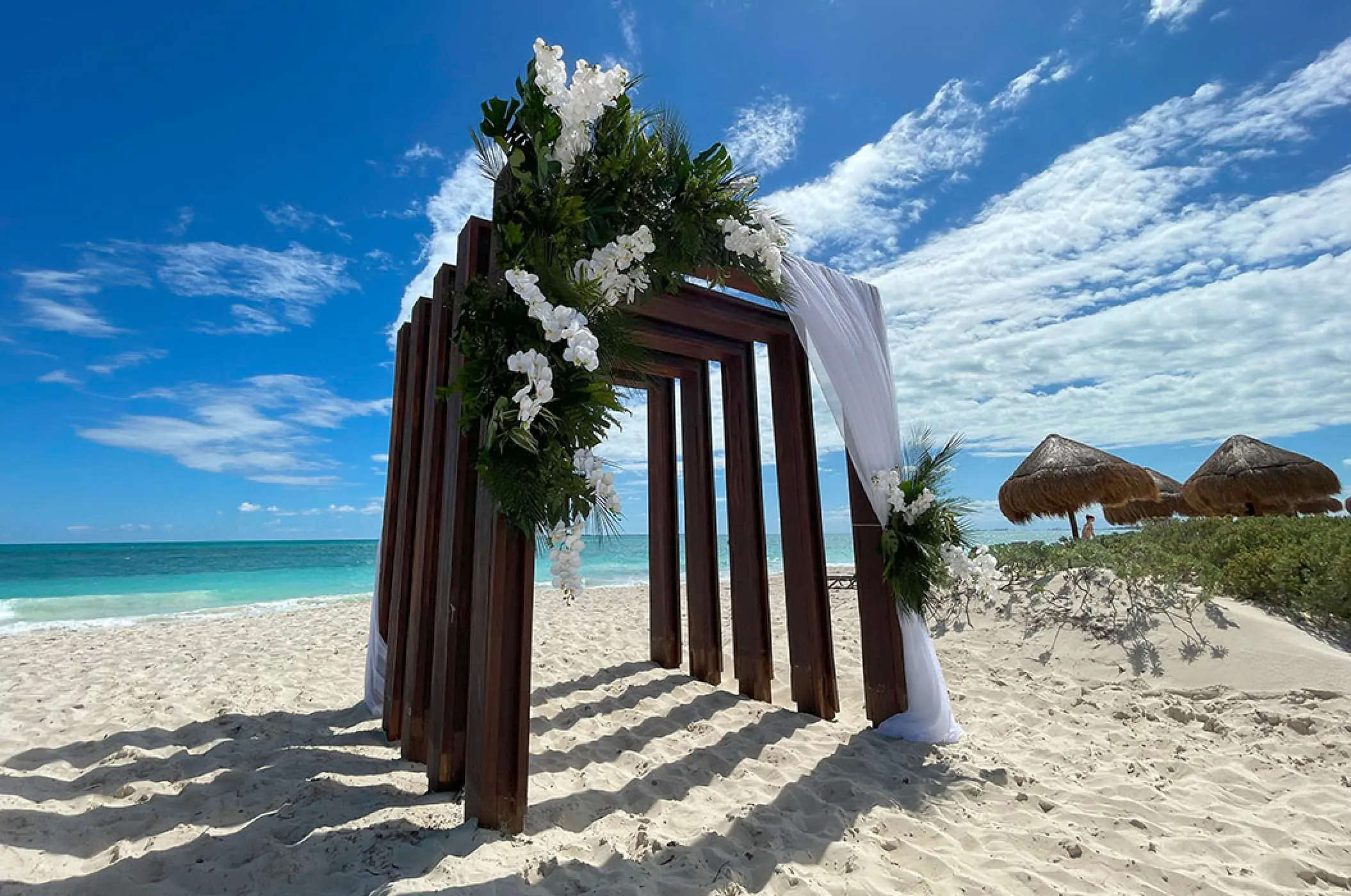 Wooden beach wedding ceremony arch with white flowers at Secrets Playa Blanca, Cancun