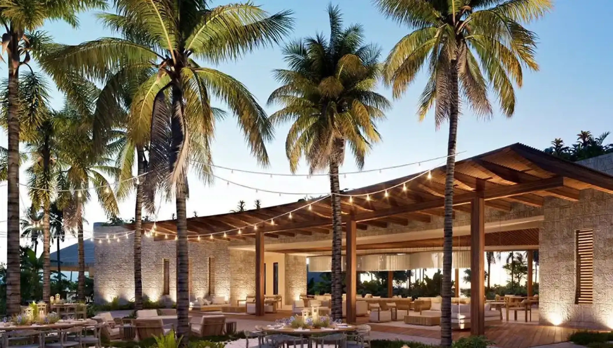 Preferred Lounge terrace under palm trees with string lights at Secrets Playa Blanca, Cancun