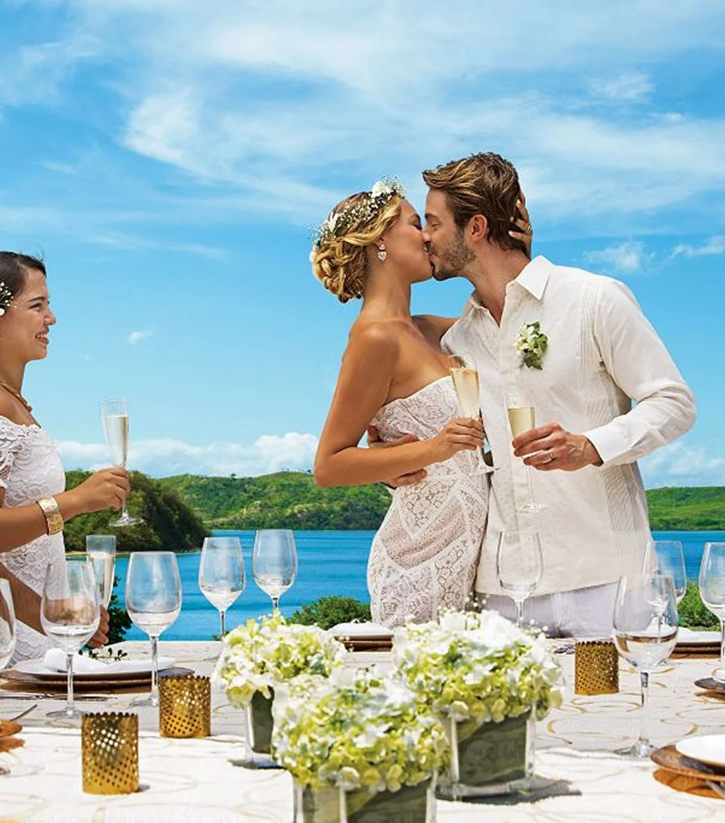 A newly married couple and their guests celebrating with champagne, overlooking a beautiful ocean view.