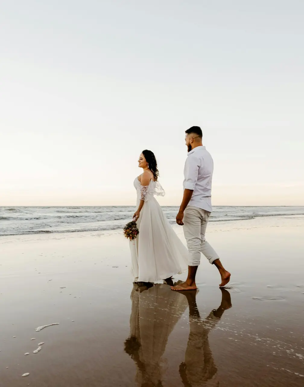Bride and groom walking on the beach at Secrets Playa Esmeralda, Miches