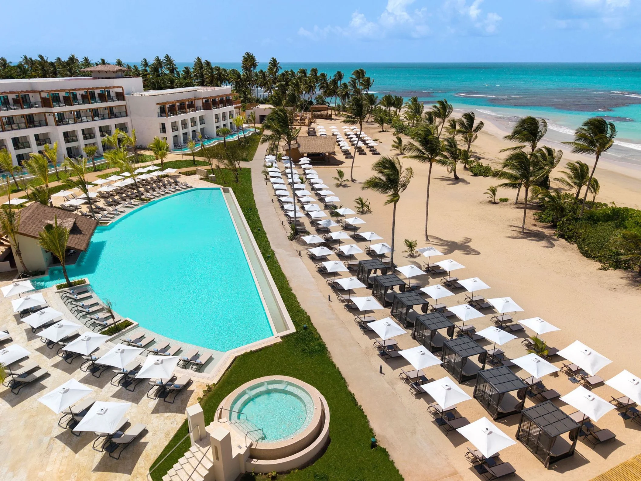 A large, multi-level swimming pool area with a hot tub and many lounge chairs for guests to relax.