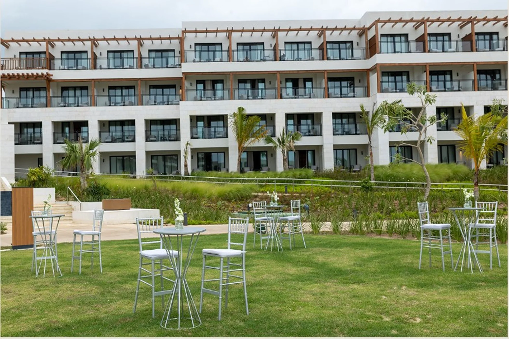 The Secrets Garden Lobby venue, a grassy lawn with cocktail tables in front of a hotel building.