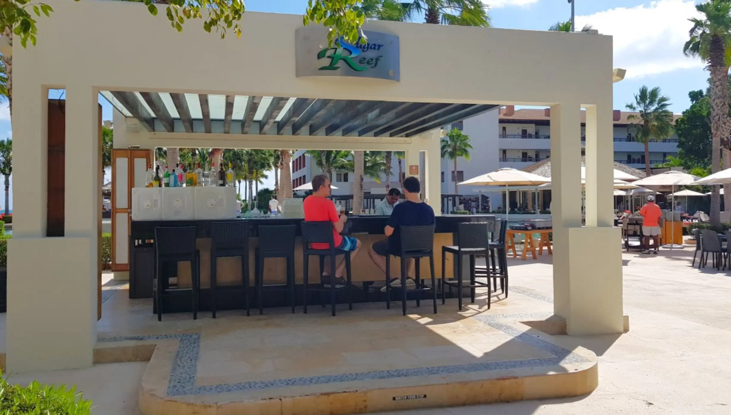 Sugar Reef Terrace bar with guests seated on stools at Secrets Playa Mujeres, Cancun