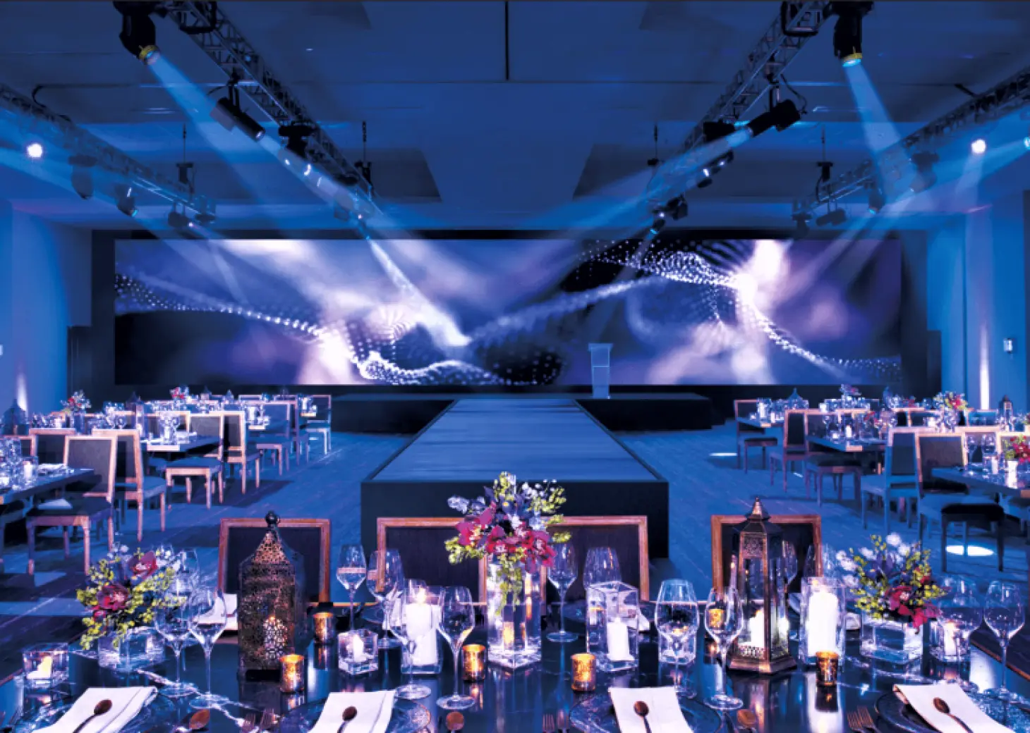 Indoor wedding reception ballroom with blue lighting and stage at Secrets Riviera Cancun, Riviera Maya