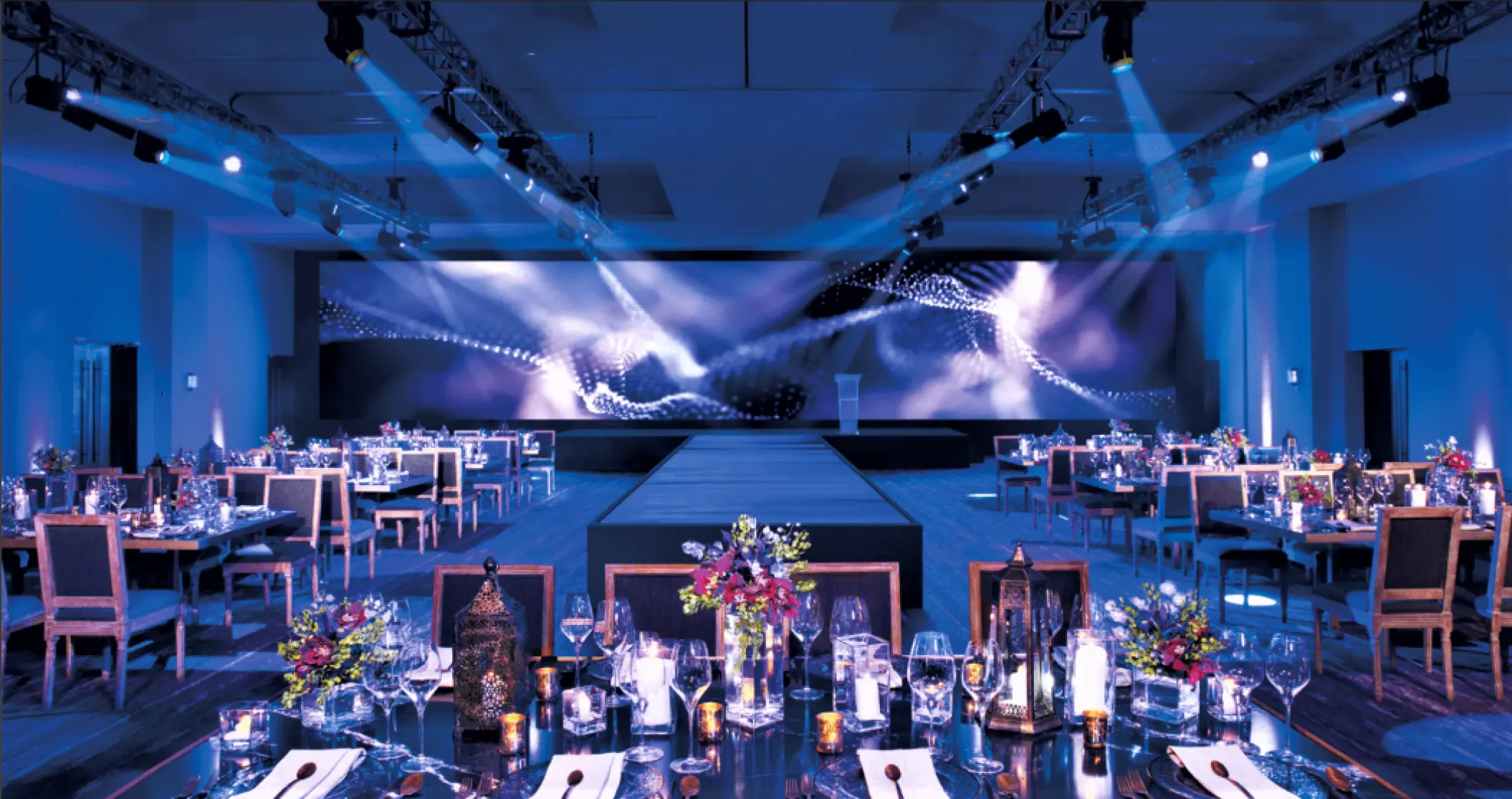 Indoor wedding reception ballroom with blue lighting and stage at Secrets Riviera Cancun, Riviera Maya