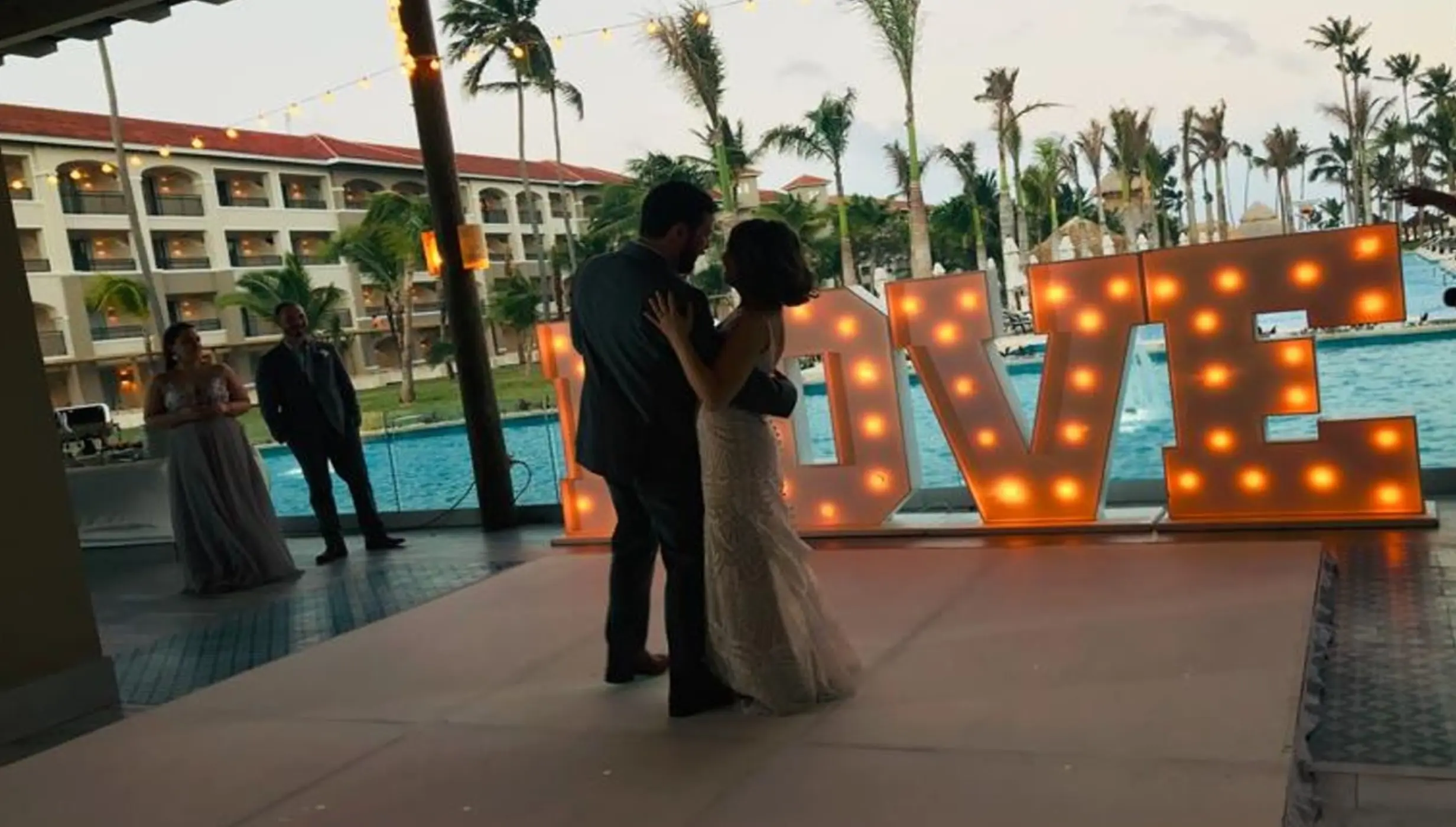 First dance on a poolside terrace next to large illuminated LOVE letters at Secrets Royal Beach, Punta Cana