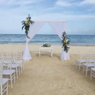 Beachfront wedding ceremony with white arch and chairs at Secrets Royal Beach, Punta Cana