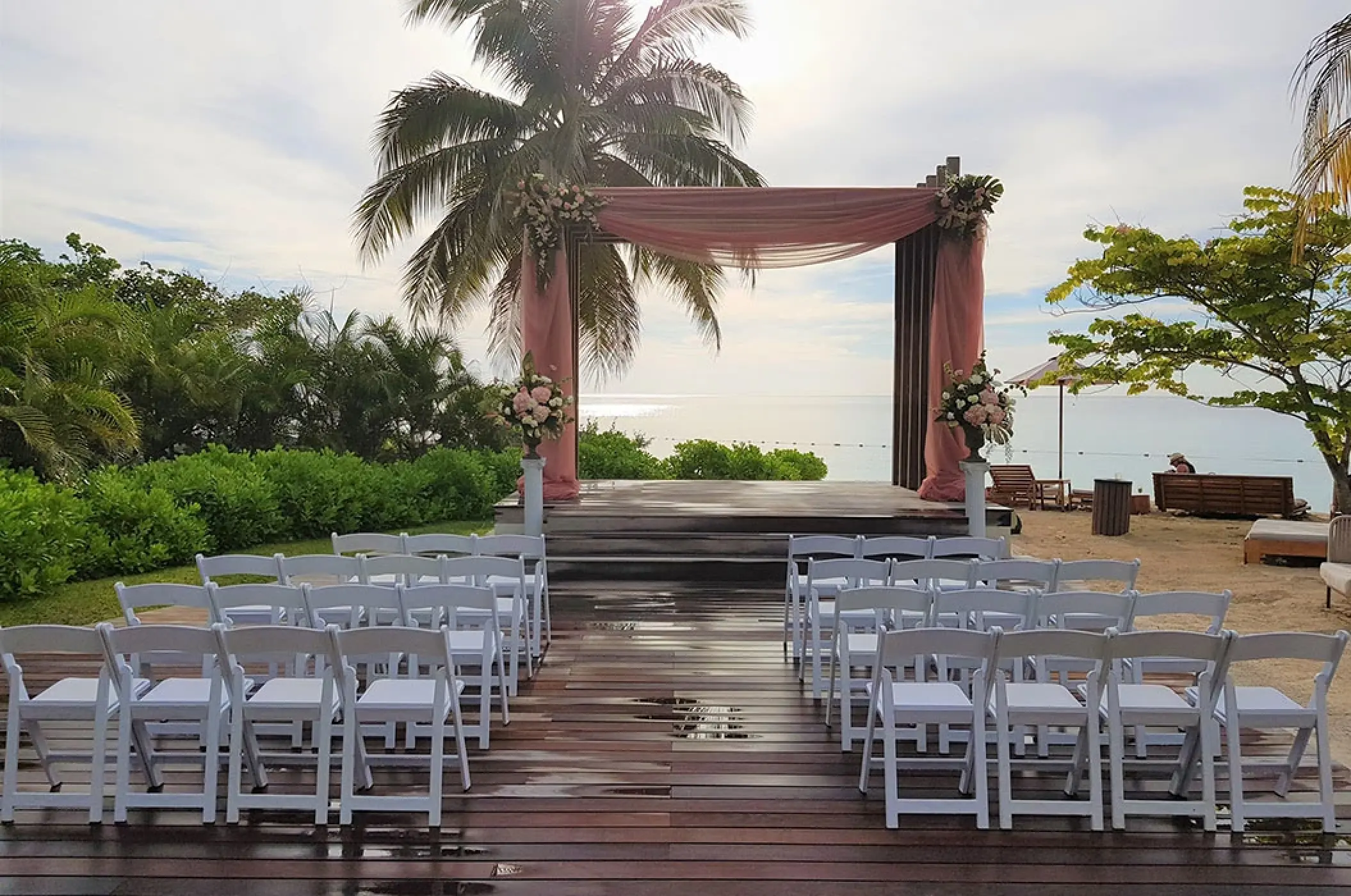Beachfront wedding ceremony setup with pink draping at Secrets St James, Montego Bay