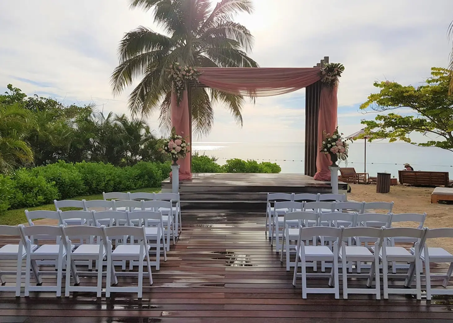 Beachfront wedding ceremony setup with pink draping at Secrets St James, Montego Bay