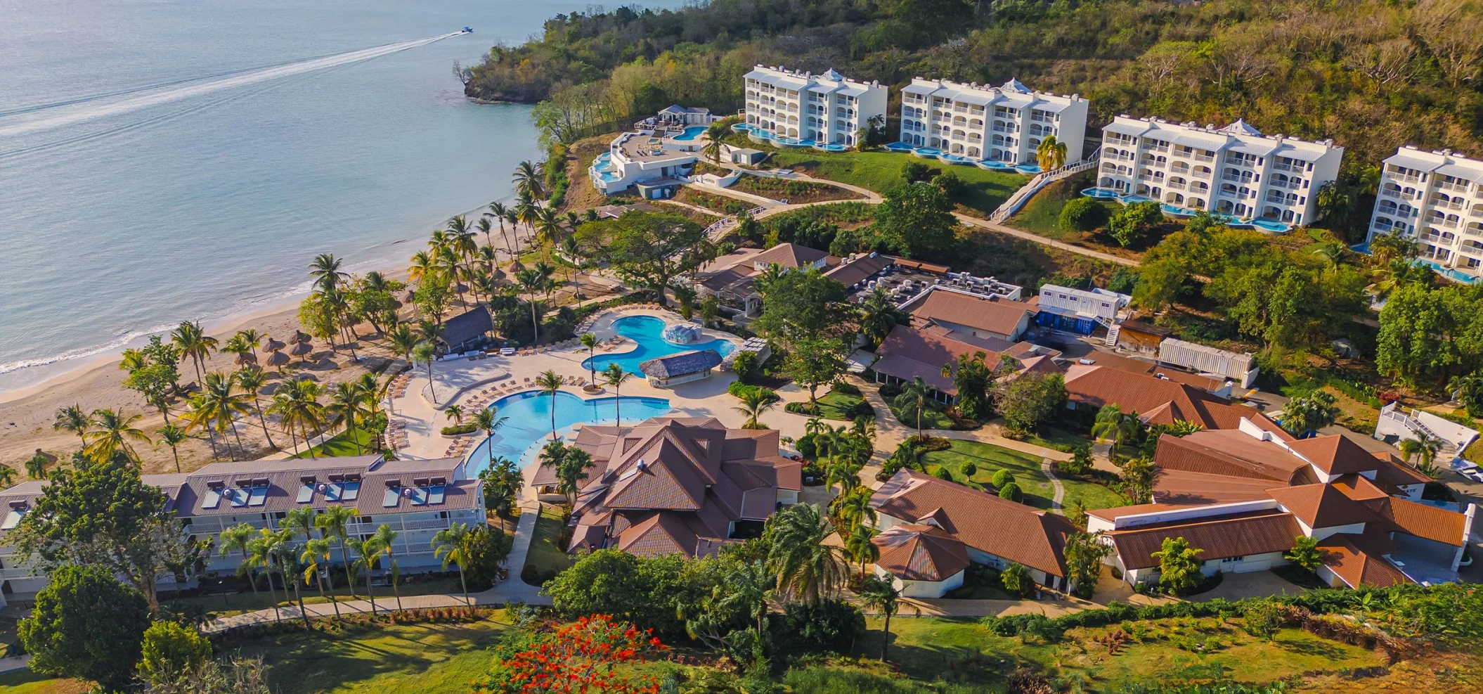 An aerial view of Secrets St. Lucia resort, showcasing pools, buildings, and a beach along the coast.
