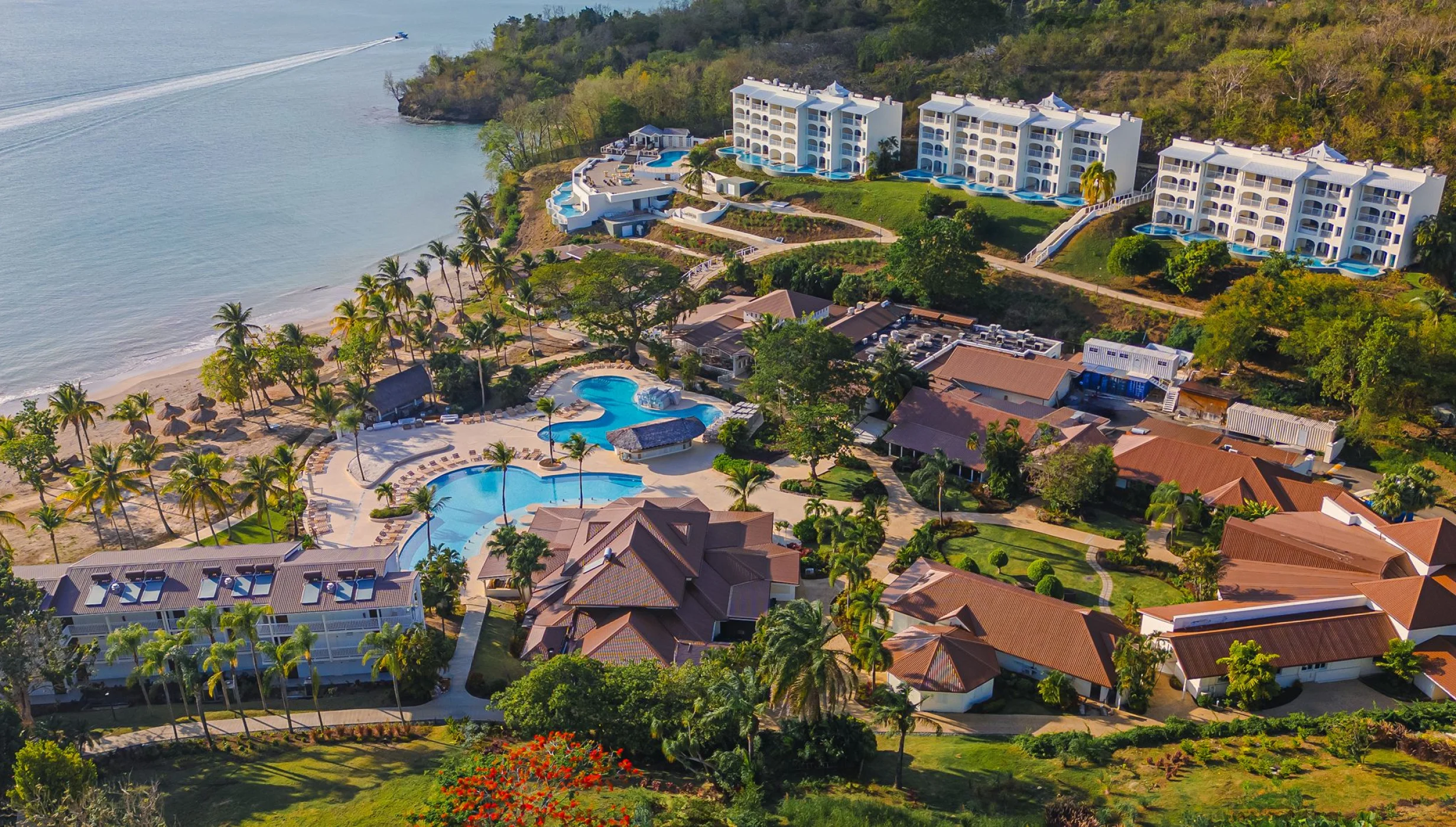 An aerial view of Secrets St. Lucia resort, showcasing pools, buildings, and a beach along the coast.