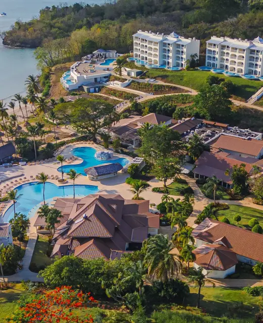 An aerial view of Secrets St. Lucia resort, showcasing pools, buildings, and a beach along the coast.