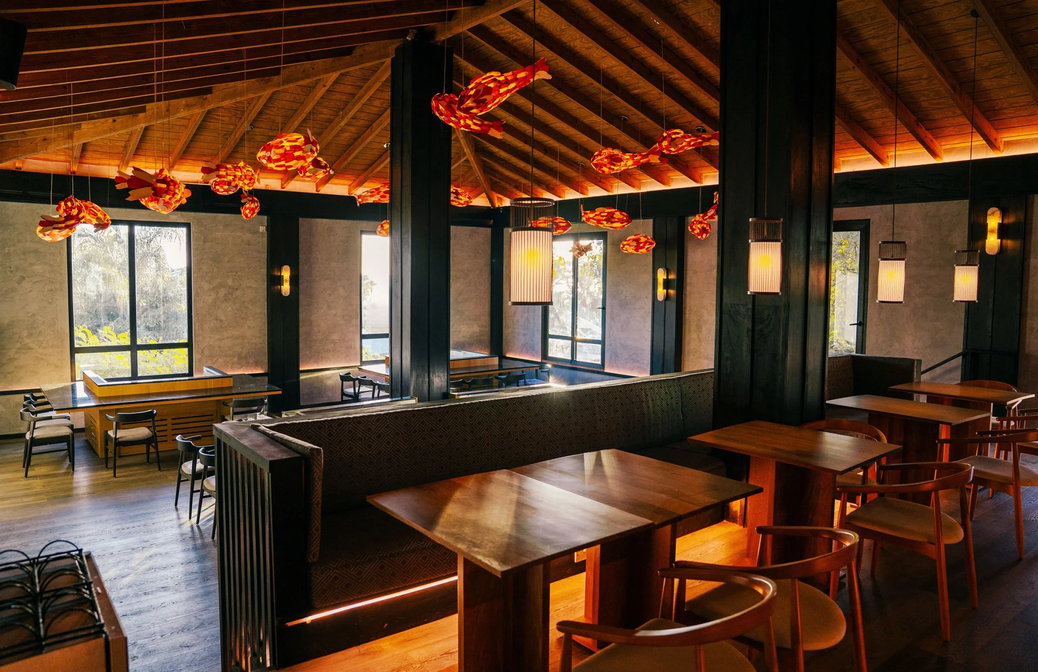 An inviting restaurant with warm lighting, wooden tables, and unique fish-shaped hanging decorations.