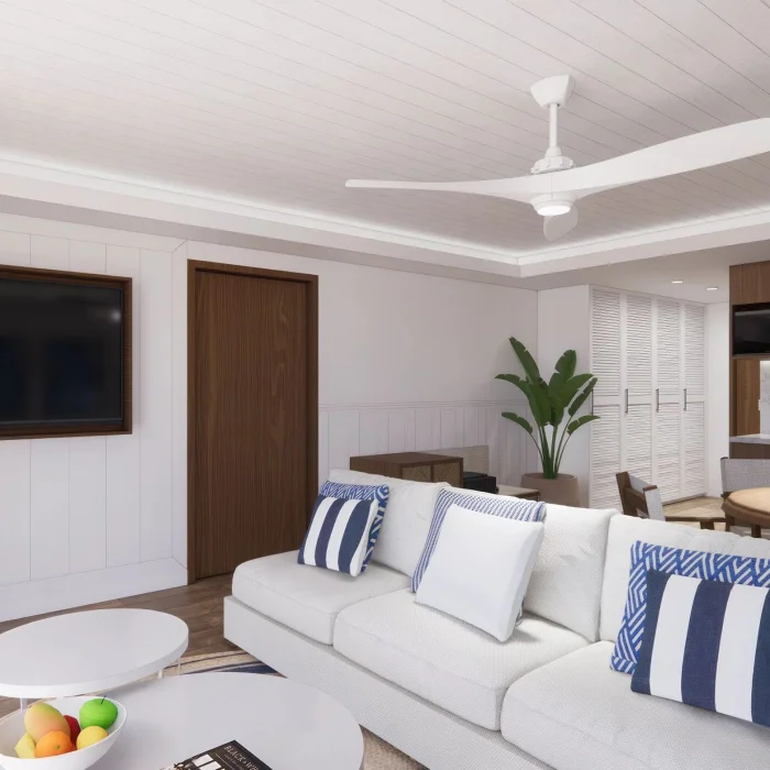 A modern living room with a white sofa, blue and white striped pillows, and a large flat-screen TV.