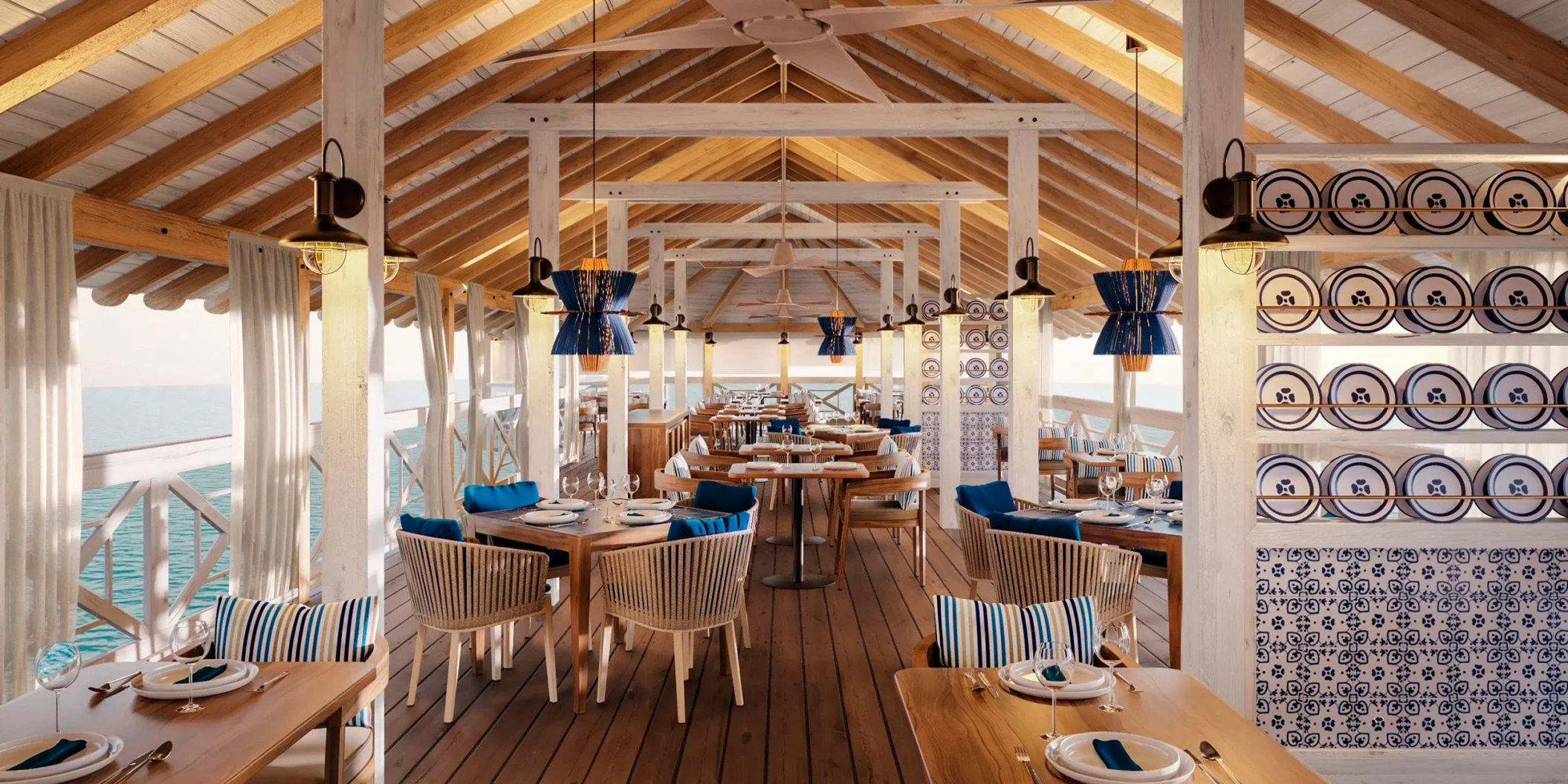A spacious overwater restaurant with high ceilings, wooden beams, and blue and white themed decor.