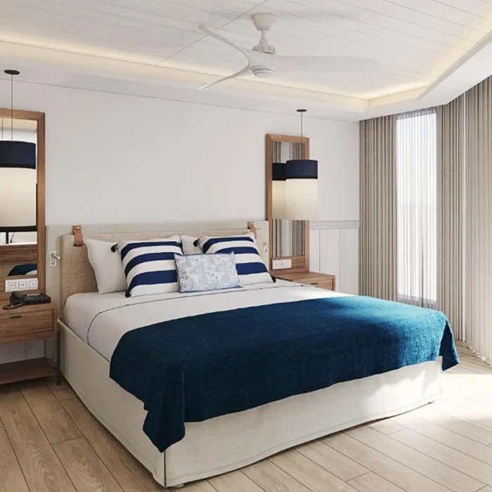 A serene hotel bedroom with a king-sized bed, white and blue bedding, and two matching nightstands.