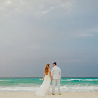 The bride and groom standing on the beach at Secrets The Vine, Cancun