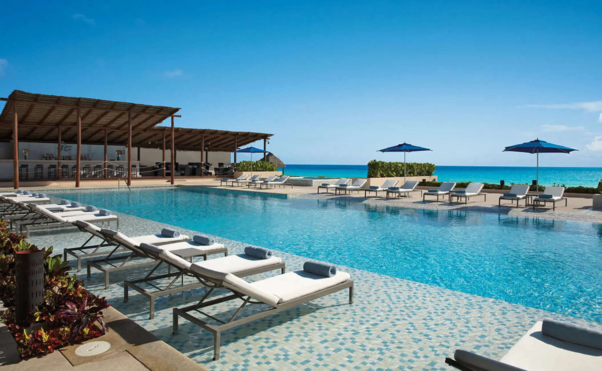 Secrets The Vine Cancun infinity pool with lounge chairs and ocean views, Cancun