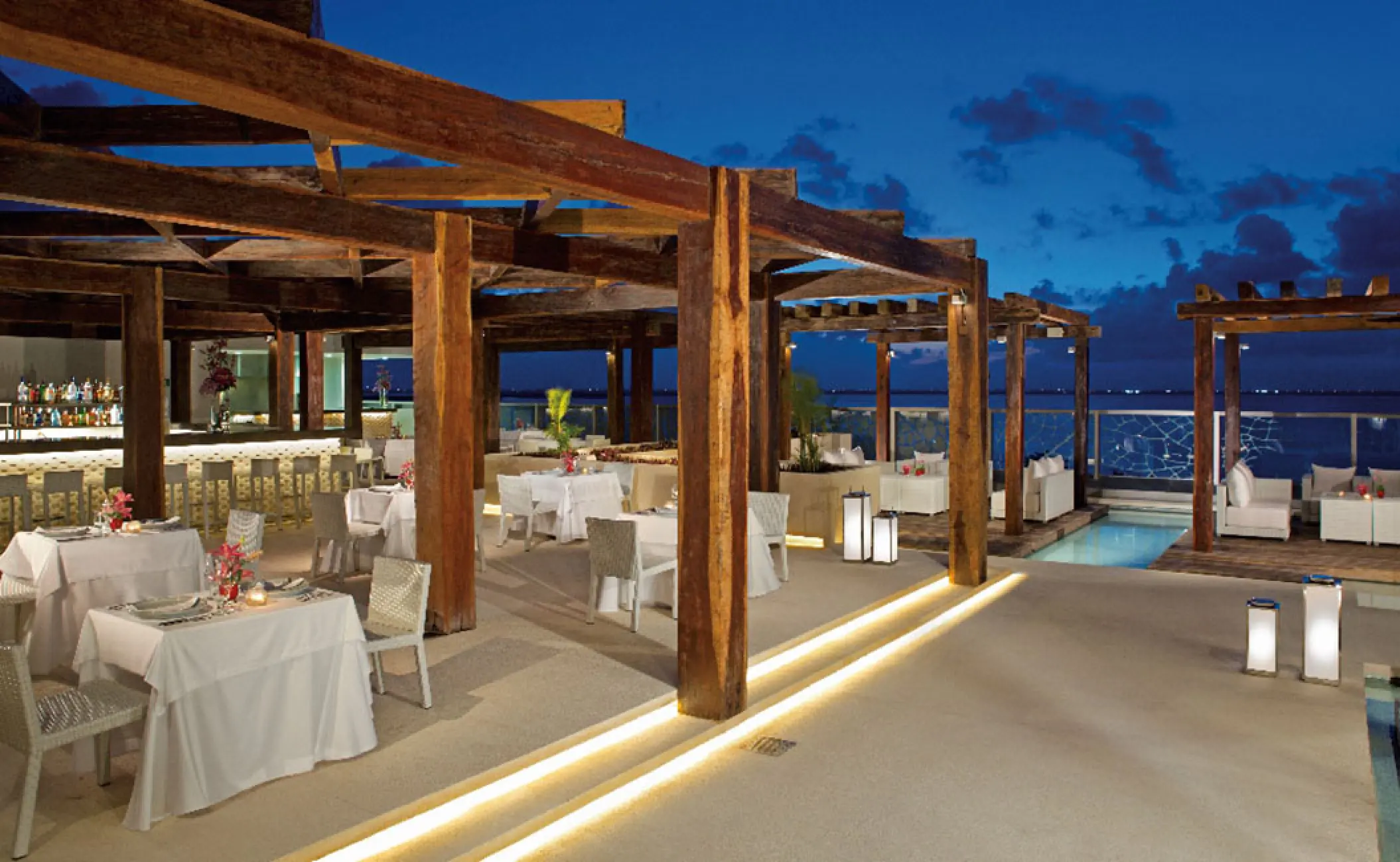 Outdoor dining terrace under a wooden pergola at Secrets The Vine, Cancun