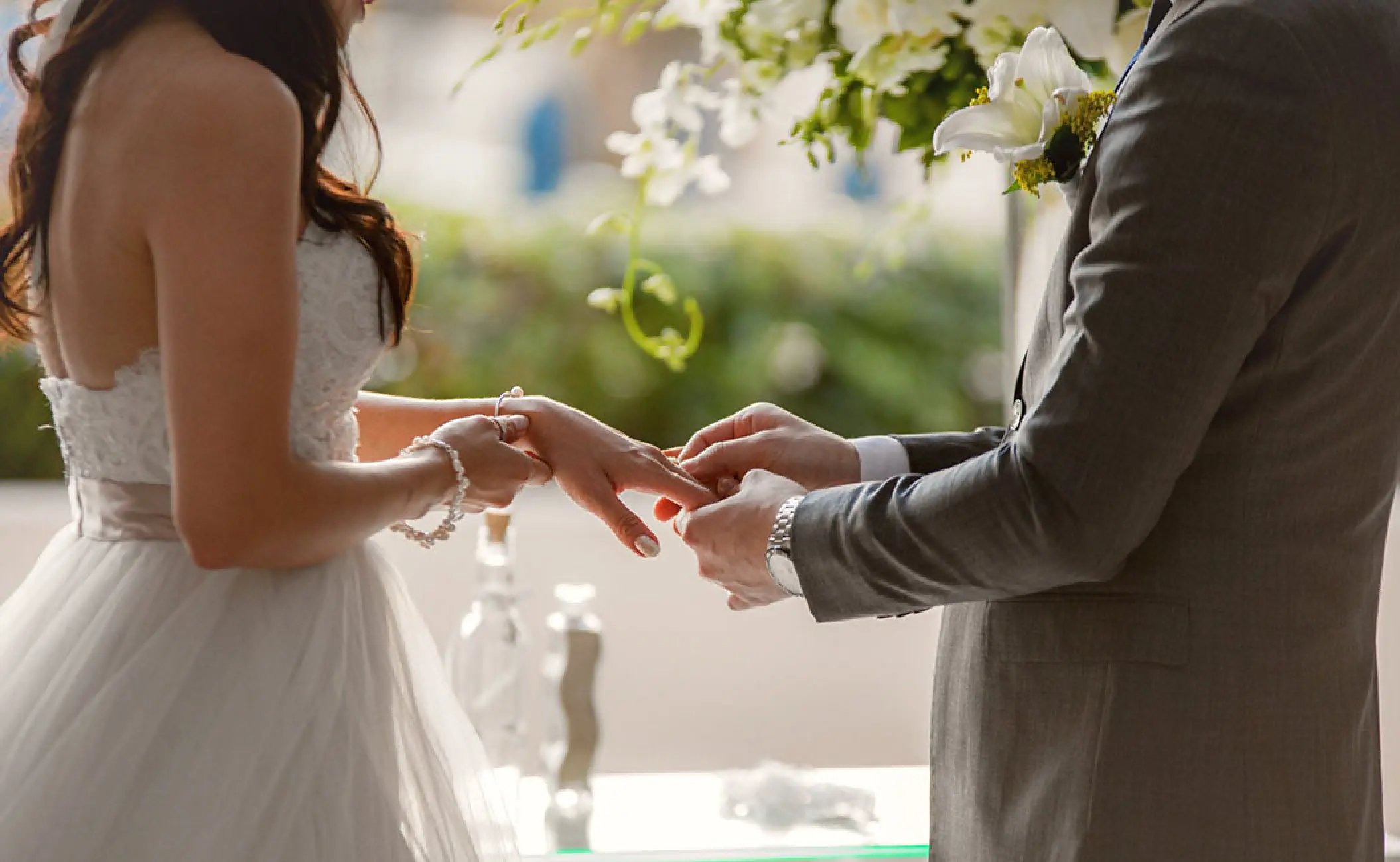 Groom placing a ring on the bride's finger during a wedding ceremony at Secrets The Vine, Cancun