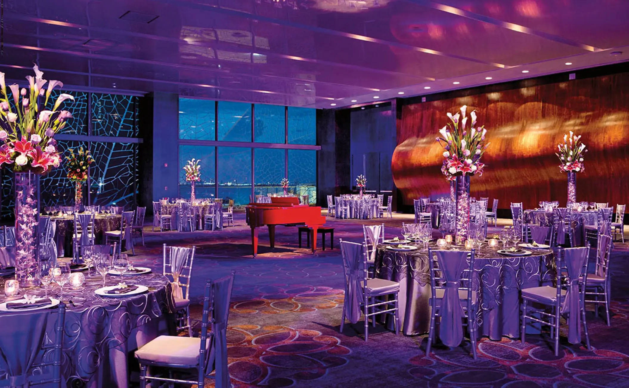 Indoor wedding reception with purple lighting and red piano at Secrets The Vine, Cancun