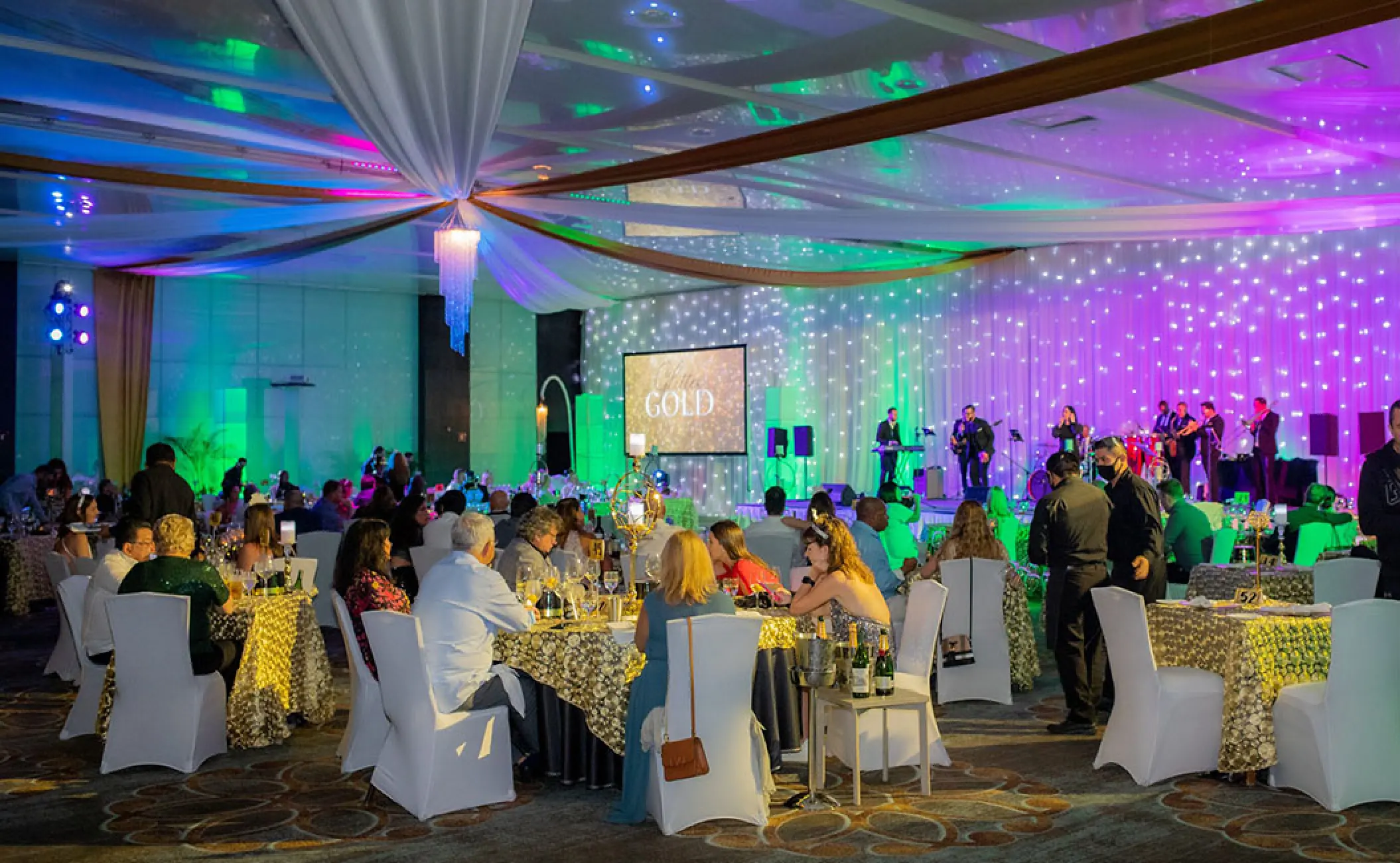 Indoor ballroom wedding reception at Secrets The Vine, Cancun featuring colorful lighting and a live band