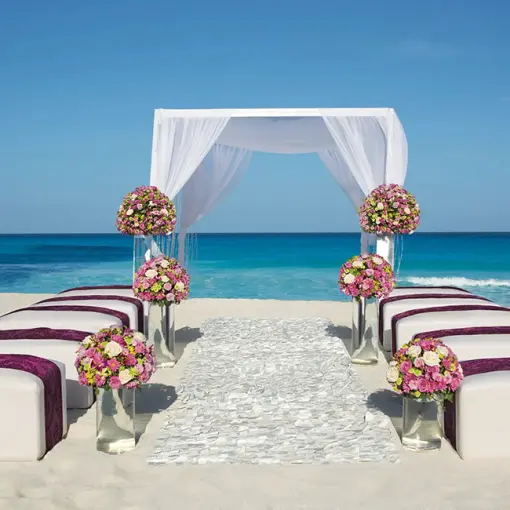 Beachfront wedding ceremony with white huppah and floral arrangements at Secrets The Vine, Cancun