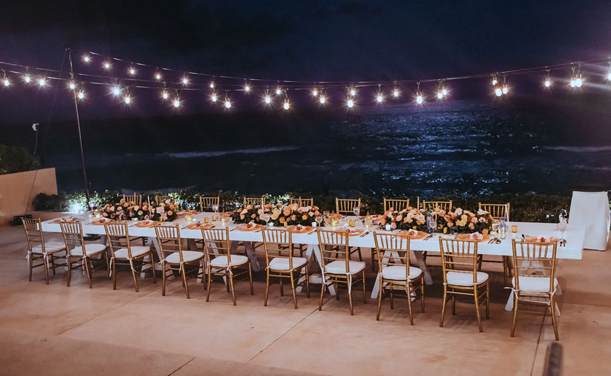Terrace wedding reception with string lights and floral centerpieces at Secrets The Vine, Cancun