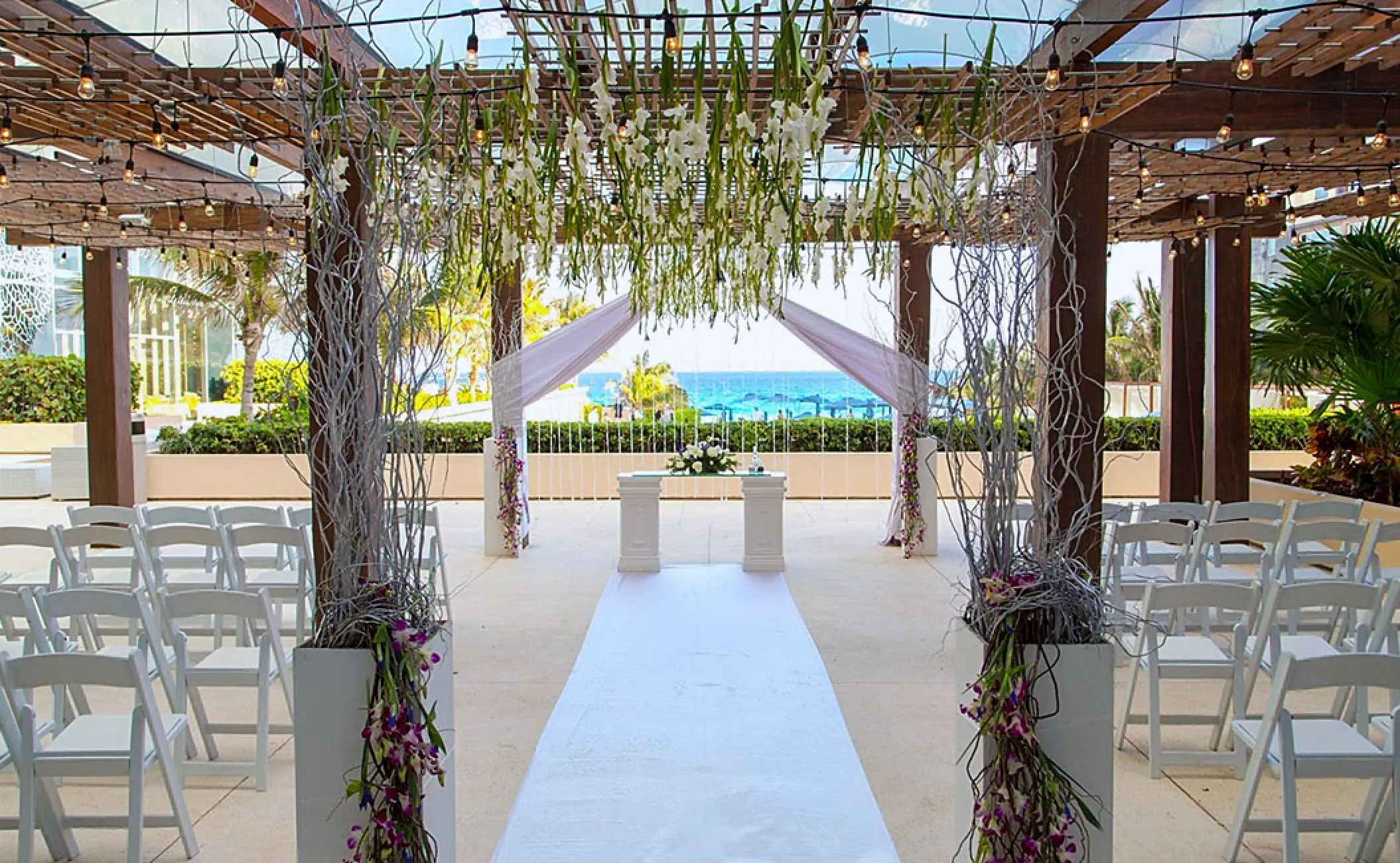 The Vine Lounge Terrace wedding ceremony setup with floral pergola at Secrets The Vine, Cancun
