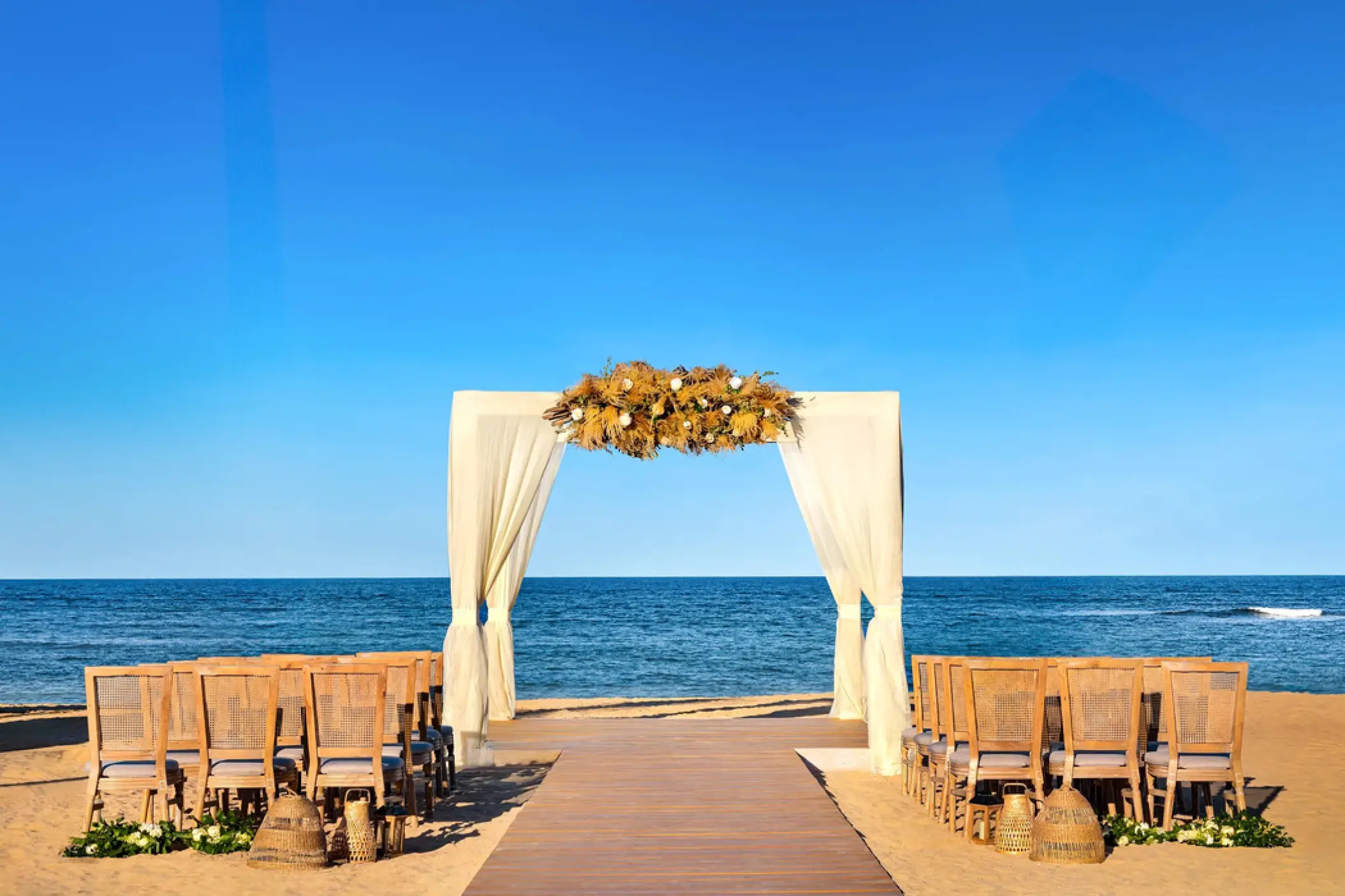 Beachfront wedding ceremony with a white draped arch at Secrets Tides, Punta Cana