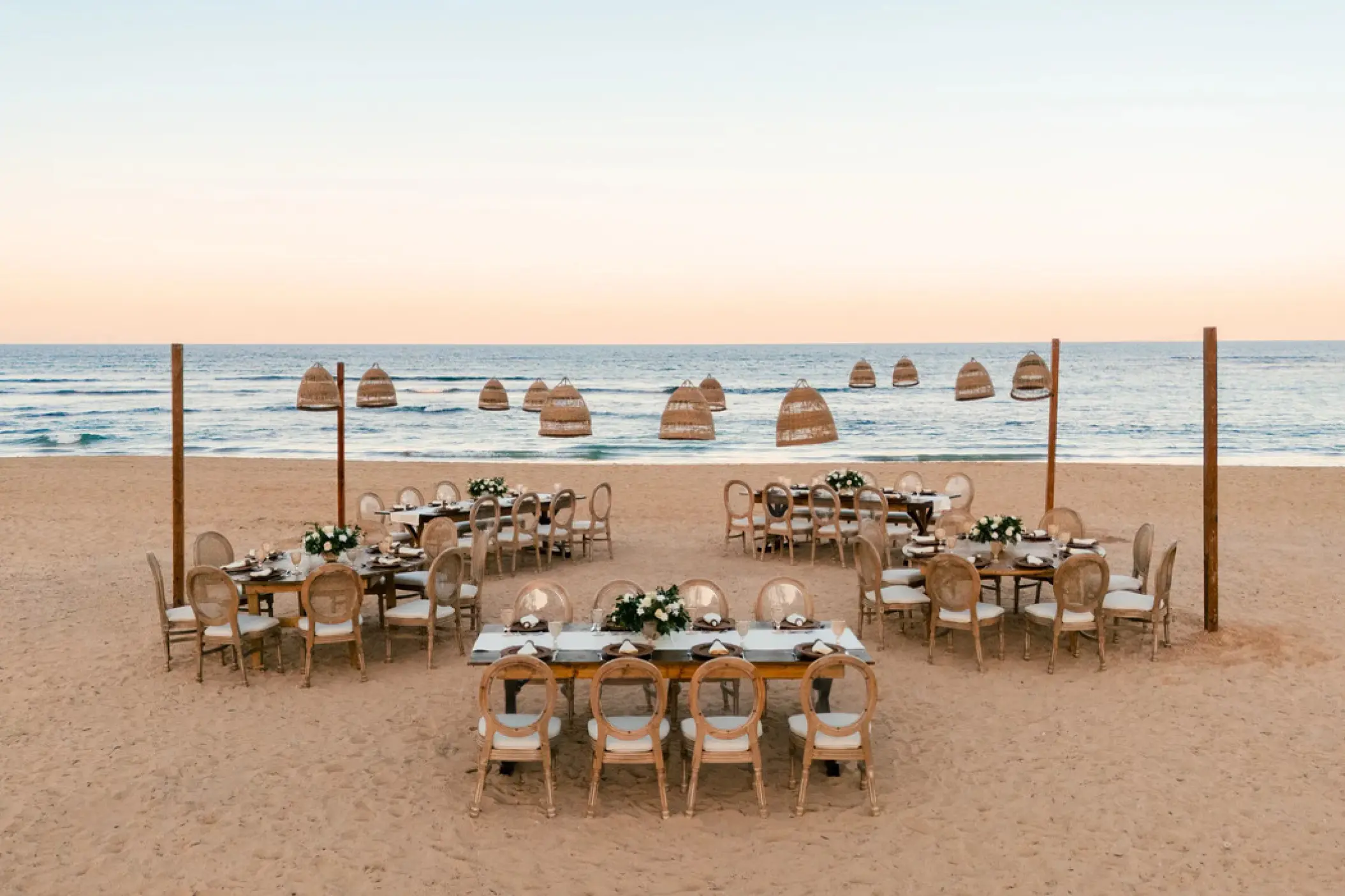 Beachfront wedding reception at Secrets Tides, Punta Cana with tables and wicker lanterns on the sand