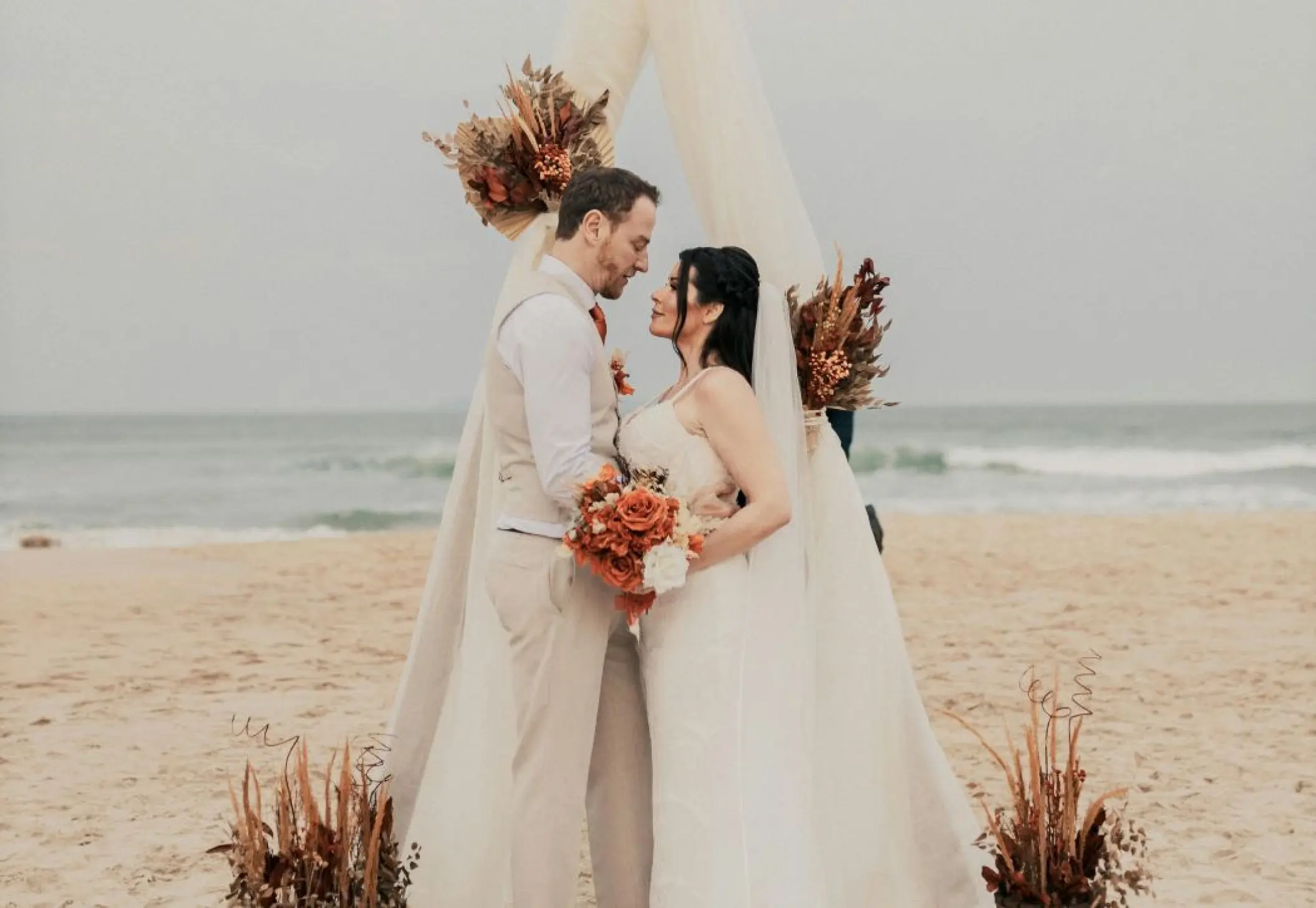 Bride and groom at a beach ceremony under a draped arch at Secrets Tides Punta Cana