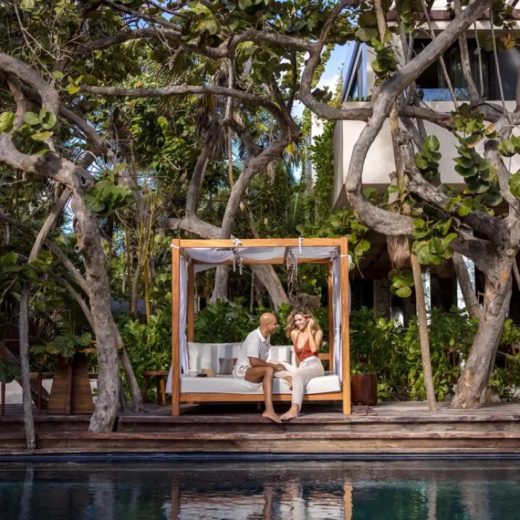 Couple relaxing in a poolside cabana surrounded by lush trees at Secrets Tulum, Tulum