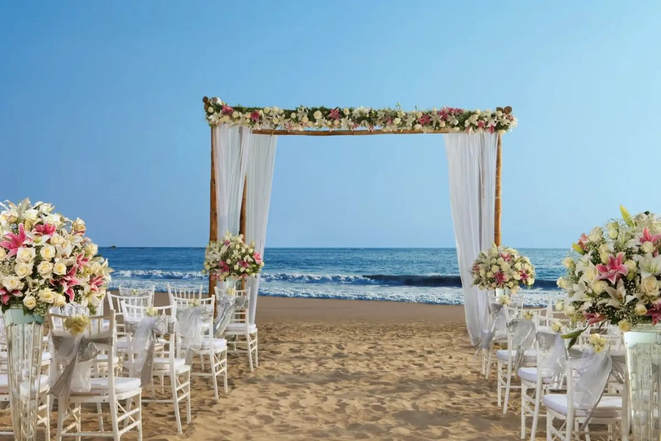 Beachfront wedding ceremony with a floral wooden arch at Secrets Vallarta Bay, Puerto Vallarta