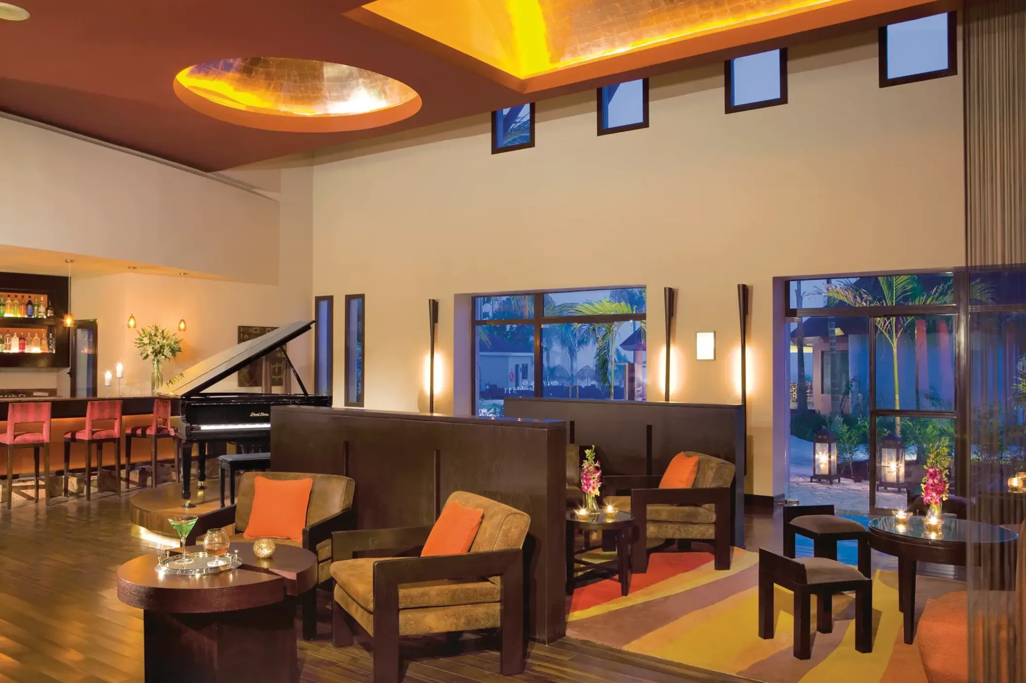 Rendezvous bar lounge with a grand piano and armchairs at Secrets Wild Orchid, Montego Bay