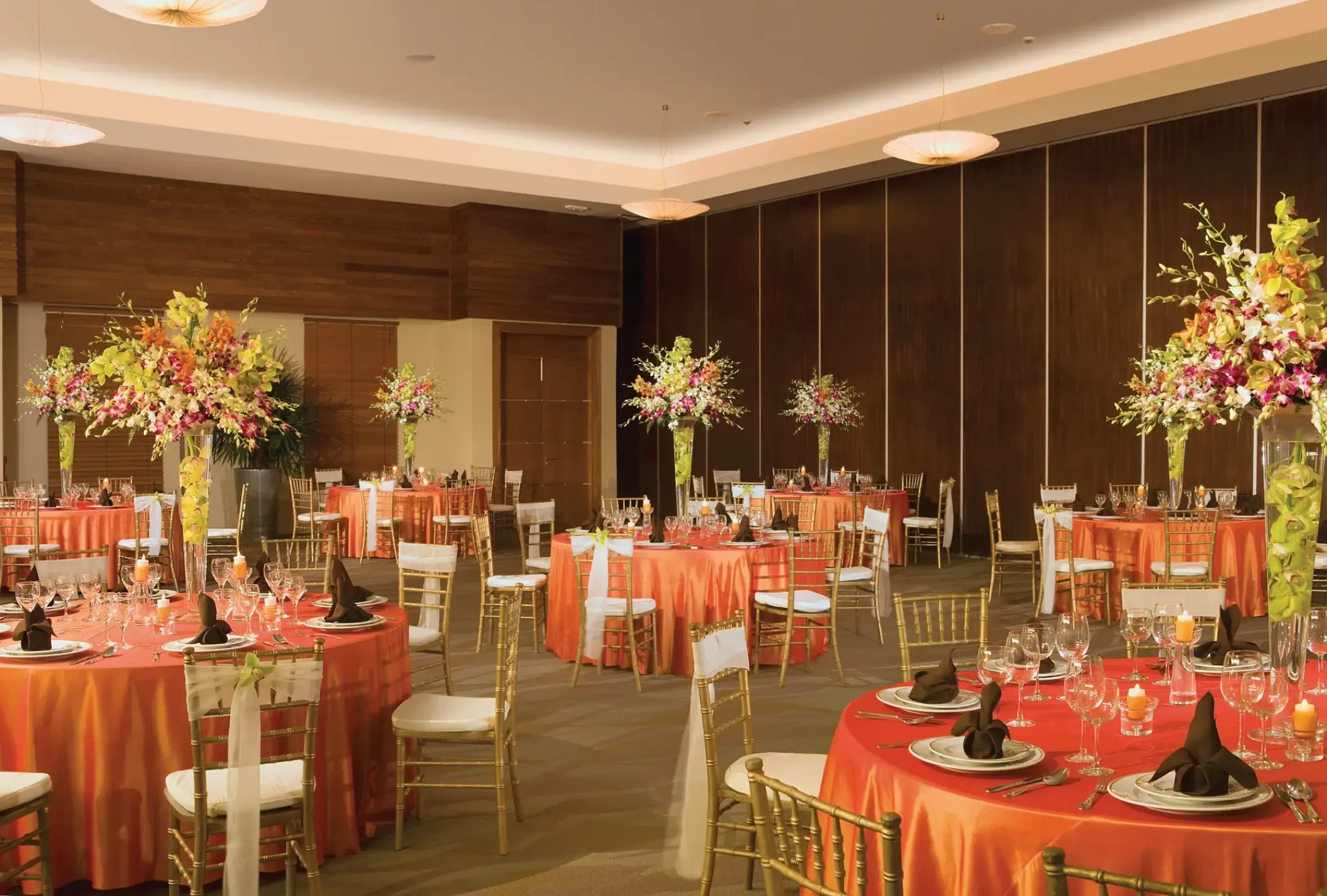 Ballroom wedding reception with orange tablecloths and tall floral centerpieces at Secrets St James, Montego Bay