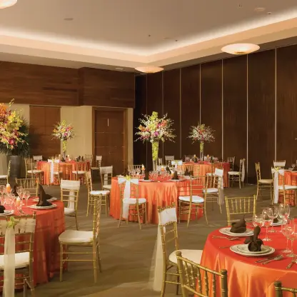 Ballroom wedding reception with orange tablecloths and tall floral centerpieces at Secrets St James, Montego Bay
